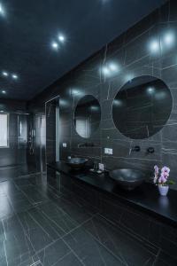 a black bathroom with two sinks and two mirrors at Marmur Suite in Palermo