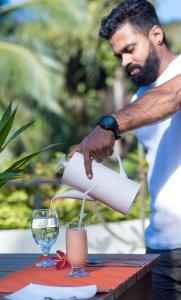 un homme verse une boisson dans un verre dans l'établissement Villa 73 Unawatuna, à Unawatuna