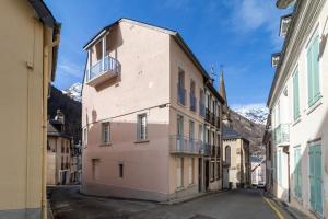 a pink building in a street with mountains in the background at La Tourette in Cauterets