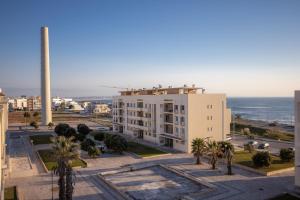 a view of a building with palm trees and the ocean at Marginal Oceanica Apartment in Buarcos