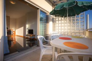 a white table with white chairs and a green umbrella at Marginal Oceanica Apartment in Buarcos