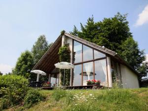 une petite maison avec des fenêtres en verre sur une colline dans l'établissement this cottage is a superb chalet, à Malmedy