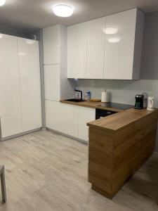 a kitchen with white cabinets and a wooden counter top at Urocza i nowoczesna kawalerka - Łódź w pobliżu centrum in Łódź