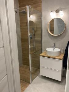 a bathroom with a shower and a sink and a mirror at Urocza i nowoczesna kawalerka - Łódź w pobliżu centrum in Łódź