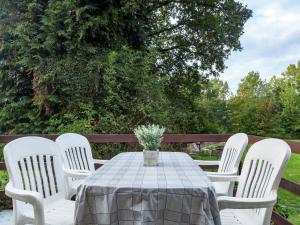 einen Tisch mit vier weißen Stühlen und einer Vase aus Blumen in der Unterkunft Holiday Home in Malmedy with terrace in Malmedy