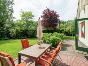 a patio table with an umbrella and chairs at Villa with spacious garden near Heeten in Heeten