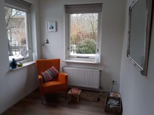 HeetenにあるVilla with spacious garden near Heetenの窓2つ付きの客室で、オレンジ色の椅子が備わります。