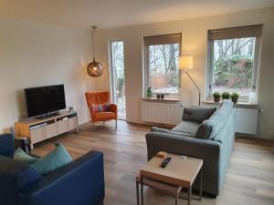 een woonkamer met 2 banken en een tv bij Villa with spacious garden near Heeten in Heeten