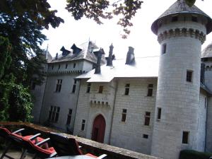 ein Schloss mit Turm und Stühlen davor in der Unterkunft Cosy castle with swimming pool in Serrières-en-Chautagne