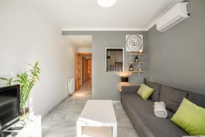 ein Wohnzimmer mit einem Sofa und einem TV in der Unterkunft EnjoyGranada TREVENQUE Center in Granada