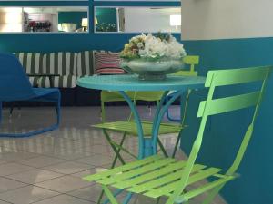 a table with a bowl of flowers and a green chair at Hotel Gialpina in Rimini