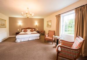 a bedroom with a bed and chairs and a window at The Frocester in Stonehouse