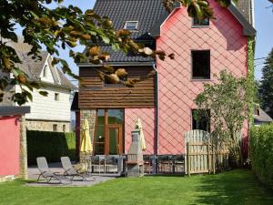 ウェームにあるSpacious Villa in Sourbrodt with Saunaのピンクの家(椅子2脚、バルコニーに犬1匹付)