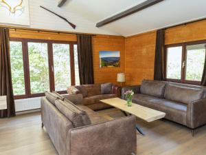 una sala de estar con muebles y ventanas de cuero. en Cosy Chalet in Odeigne with Jacuzzi, en Manhay