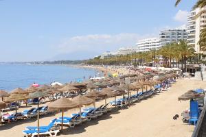 plaża z leżakami i parasolami oraz ocean w obiekcie Residencial las Flores Marbella w Marbelli