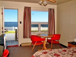 a bedroom with a table and chairs and a view of the ocean at Hôtel-Motel Le Pharillon in Cap-des-Rosiers