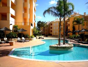 una piscina con una palmera frente a un edificio en Estrela da Luz 1 bedroom apt pool and sea views, en Alagoas