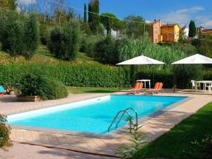 uma piscina num quintal com cadeiras e guarda-sóis em Belvilla by OYO Massarella Due em Fucecchio