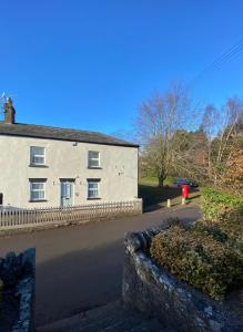 a white house with a fence next to a street at Jollys of Goodrich in Goodrich