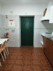 a kitchen with a green door and a tile floor at Casas da Saibreira - nº10 in Elvas