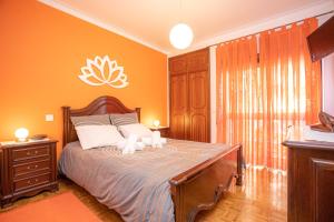 a bedroom with orange walls and a bed with two candles on it at Tamargueira Beach Apartment in Buarcos