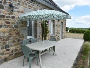 einen Tisch und Stühle unter einem Sonnenschirm auf einer Terrasse in der Unterkunft Tasteful holiday home in Plouvara with garden in Saint-Donan