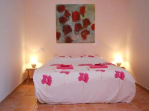 a bedroom with a white bed with pink flowers on it at Beautiful appartment with pool in Provence in Valréas