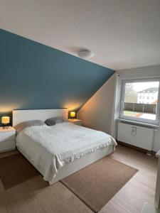 - une chambre avec un lit et un mur bleu dans l'établissement Ostseeauszeit Blengow, à Rerik
