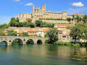 a bridge over a river with a castle in the background at Old wine storehouse with terrace and garden in Puimisson