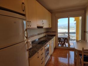 uma cozinha com um frigorífico e uma mesa com uma varanda em Dúplex en 1ª línea de playa em Foz