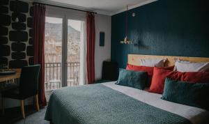 a bedroom with a bed with colorful pillows and a window at Hotel Spa Azteca Barcelonnette in Barcelonnette