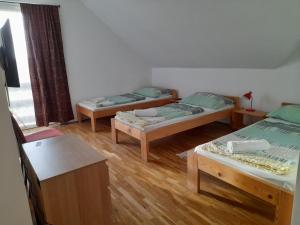 three beds in a room with wooden floors at Anna Vendégház Szeleste in Szeleste