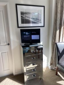a television sitting on a glass table with a drawer at Gretenham B&B in Swanage