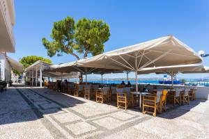 a group of tables and chairs under umbrellas on the beach at Hotel Roumani in Spetses