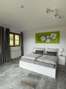 una camera da letto con un grande letto bianco con fiori sul muro di Casa de la Paz, Millstatt - geräumige neu ausgestattete FeWo mit Seeblick und Bergpanorama a Millstatt