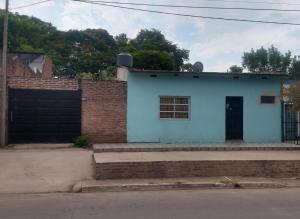 a blue house with a brick wall and a door at Alborada Hostel in Resistencia