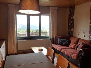 a living room with a couch and a table and a window at Luxurious farmhouse near the ski area in Hellenthal