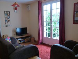 a living room with two chairs and a tv and a door at Chalet with garden in the Pyrenees in Roquefort-de-Sault