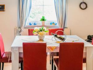 a dining room table with red chairs and a vase of flowers at Modernes Familienapartment in Medebach