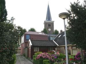 een kerk met een toren en een klokkentoren bij Holiday home near the Frisian Eleven Cities in Mantgum