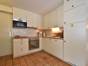 een keuken met witte kasten en een magnetron bij Authentic cottage nearby a beautiful forest in Lierneux