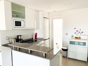 a white kitchen with a sink and a microwave at Sol Blanco in Arenales del Sol