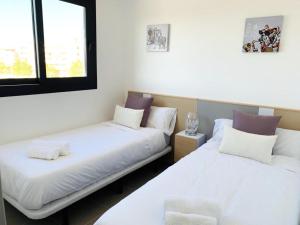 two beds in a room with two windows at Sol Blanco in Arenales del Sol