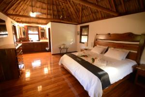 a bedroom with a large bed and a wooden floor at El Ben Cabañas in Caye Caulker