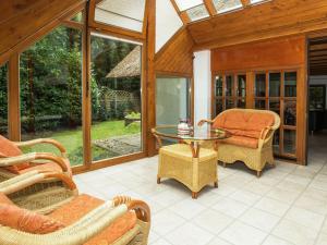 un porche cubierto con mesa de cristal y sillas en Exclusive holiday home in Uelsen with conservatory, en Uelsen