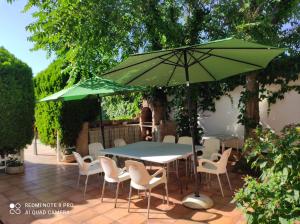una mesa y sillas bajo una sombrilla en un patio en CASA RURAL TRES VENTAS, en Brazatortas