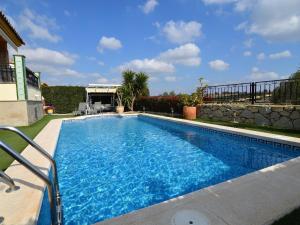 a swimming pool with blue water in front of a house at Belvilla by OYO Villa Orange in Algorfa