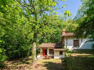 a small white house with a red door in the woods at Belvilla by OYO Due Camini in San Marcello Pistoiese