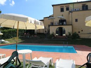 een zwembad met stoelen en een parasol naast een huis bij Belvilla by OYO Villa Gaio in Vicchio