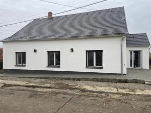 een wit huis met zwarte ramen op een straat bij WBR. vendégház in Villány